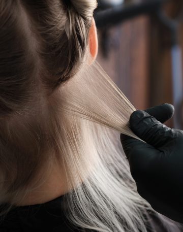 A young woman in a hairdressing salon dyes her hair blond. Hair coloring process